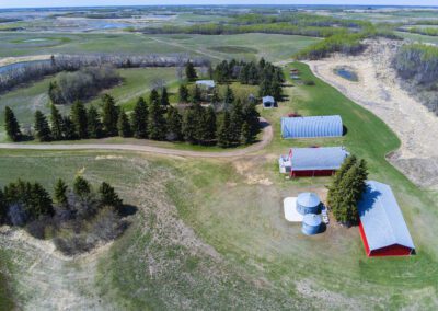 Bird's-eye view of a rural farm with a traditional barn and a cozy house set in a lush landscape.