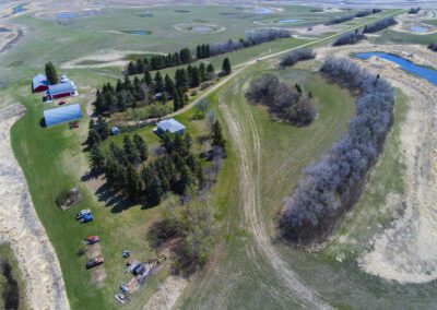 Overhead perspective of a farm showcasing a barn and a house amidst expansive agricultural land.