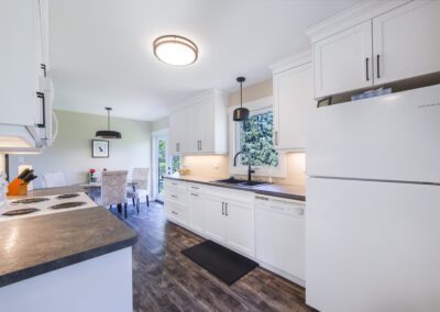 A modern kitchen featuring sleek white cabinets and a stainless steel refrigerator, creating a bright and inviting atmosphere.