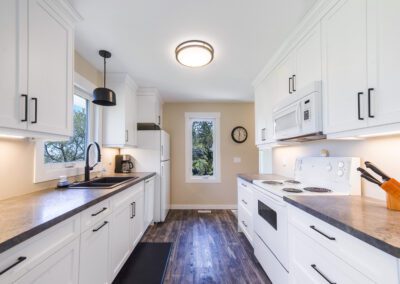 A stylish kitchen showcasing white cabinetry and a contemporary refrigerator, emphasizing cleanliness and elegance in design.